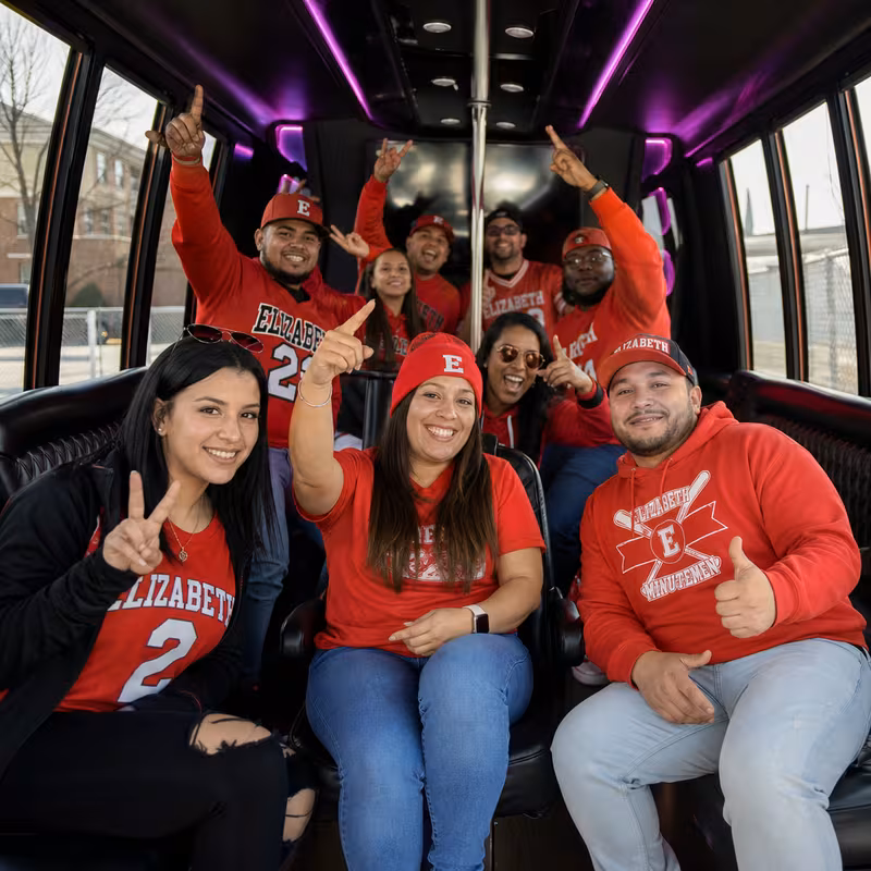 Group boarding a white charter bus for Sporting Event Transportation transportation in Elizabeth